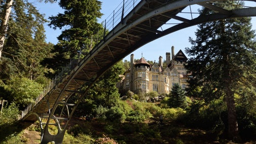 Cragside House framed under the grand arch of Cragside's industrial Iron Bridge.
